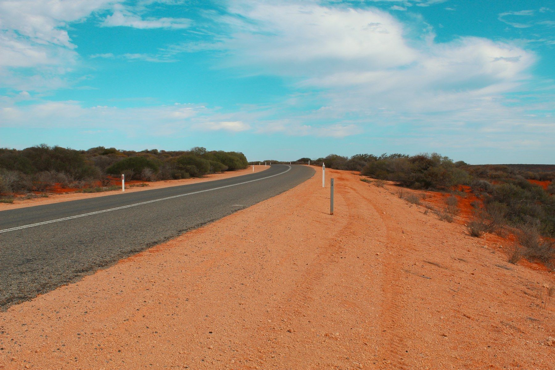 Empty outback road through red dirt and scrub